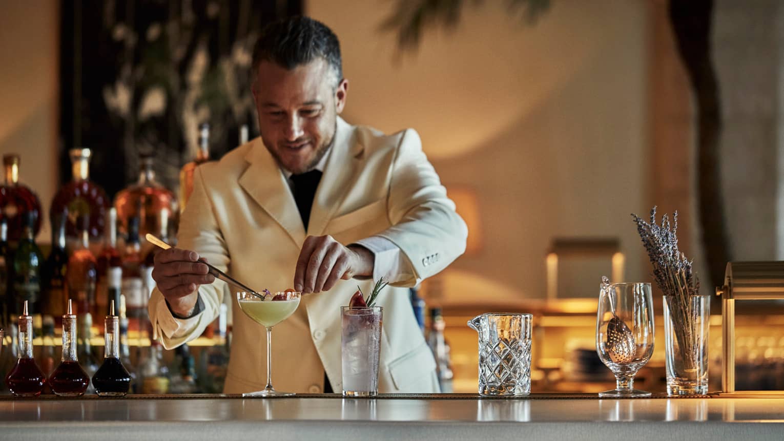 Surf Club Ballroom. Mixologist in a white suit stands behind the bar, garnishing signature Mangareva cocktail