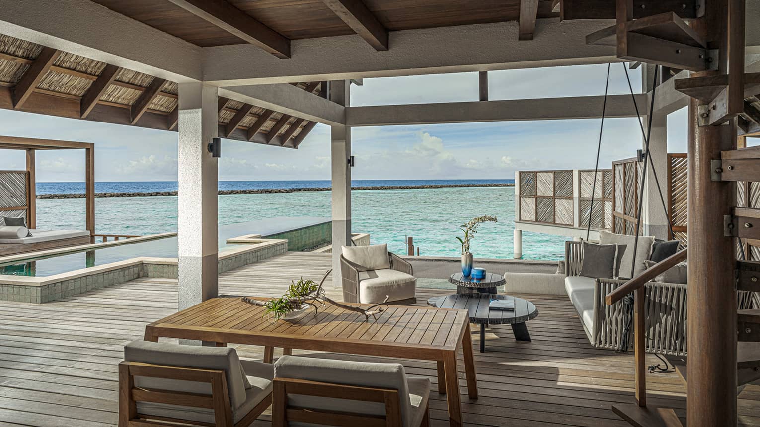 Covered wooden deck of villa over the ocean with pool