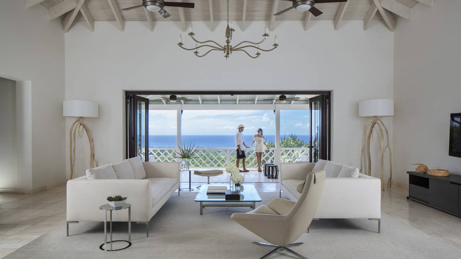 Living room with modern white furniture in front of open doors to sunny patio, couple