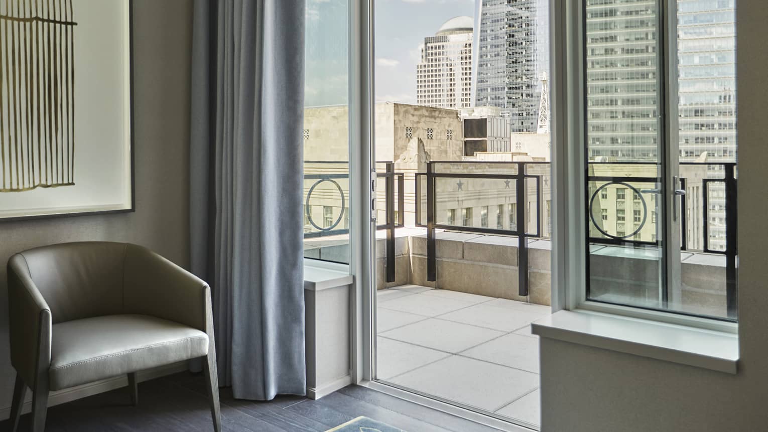Tribeca Suite leather mid-century style chair by open door to tile balcony overlooking downtown New York