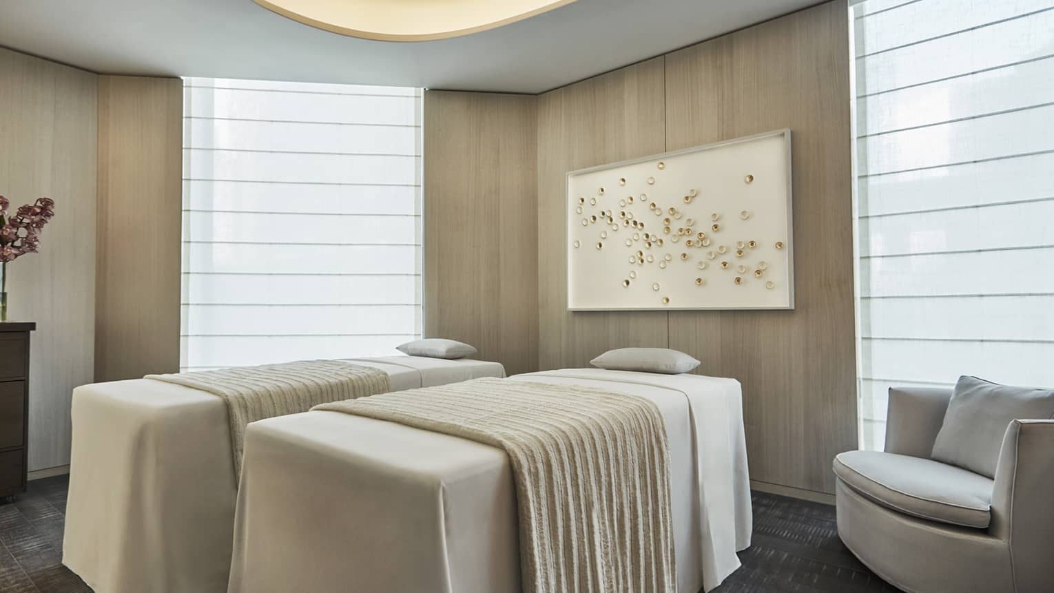 Side-by-side massage tables with white blankets in spa room