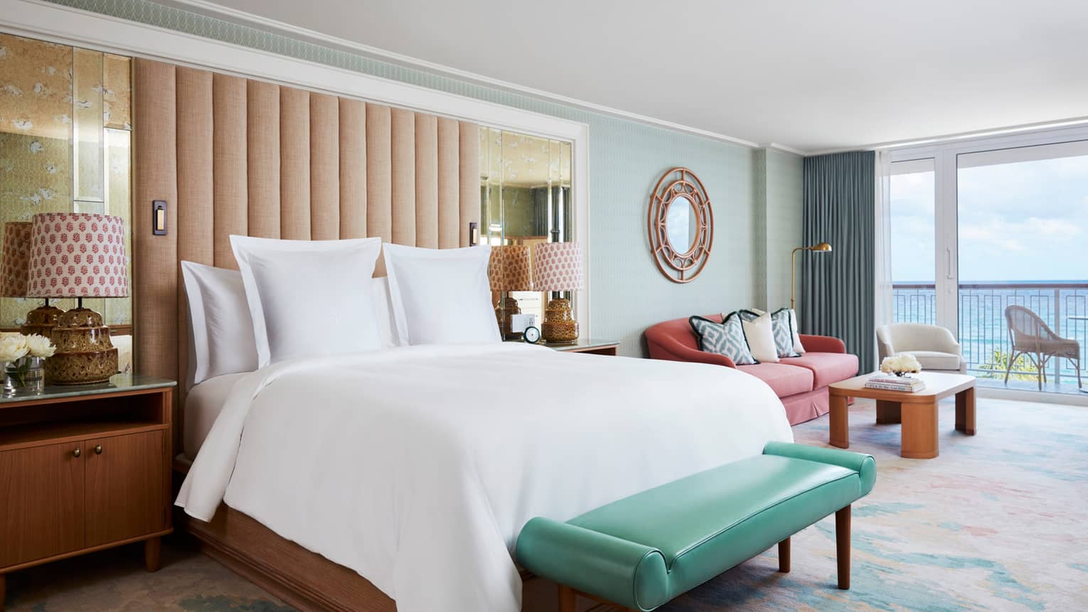 Ocean View Studio Suite bed and teal leather bench by seating area, balcony door