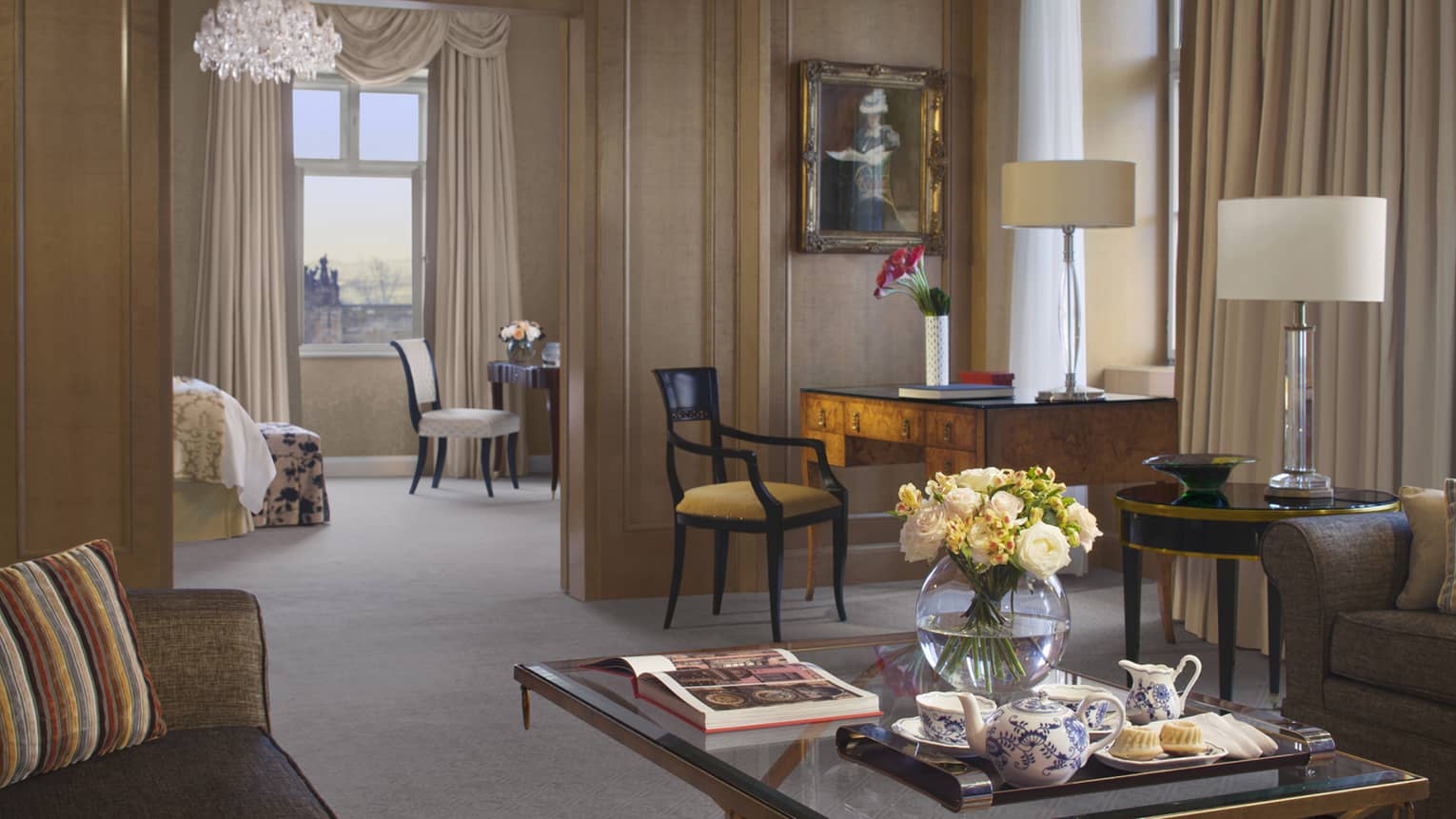Premier Suite living room, glass coffee table with open book, round glass vase with white roses, tea service 