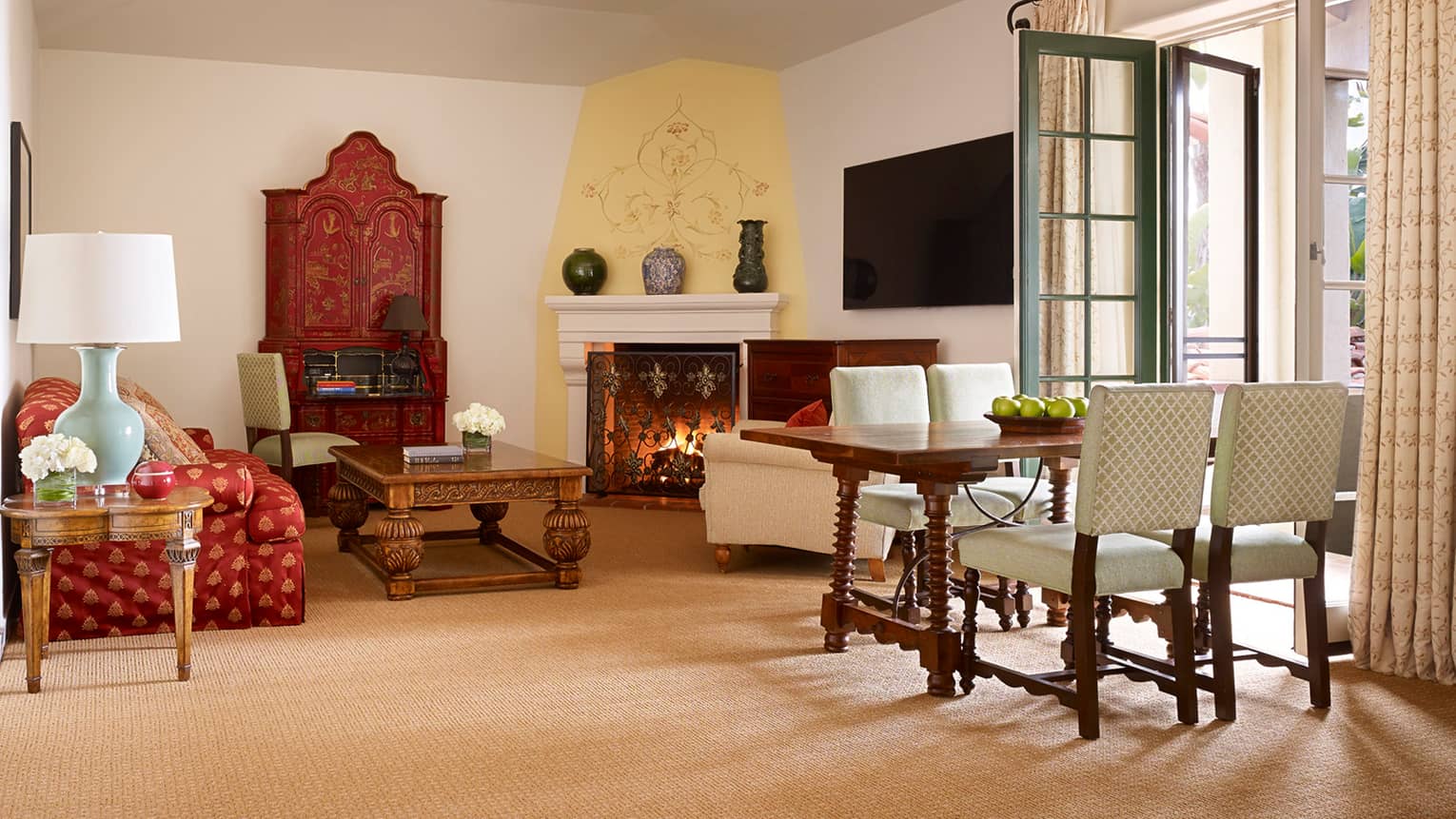Bright Santa Cruz Suite with red silk sofa, carved wood table by fireplace, table, French doors