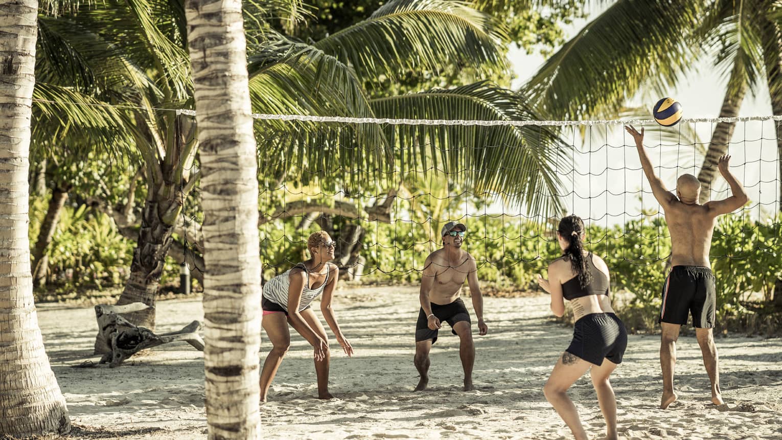 Friends playing beach volleyball on sunny day