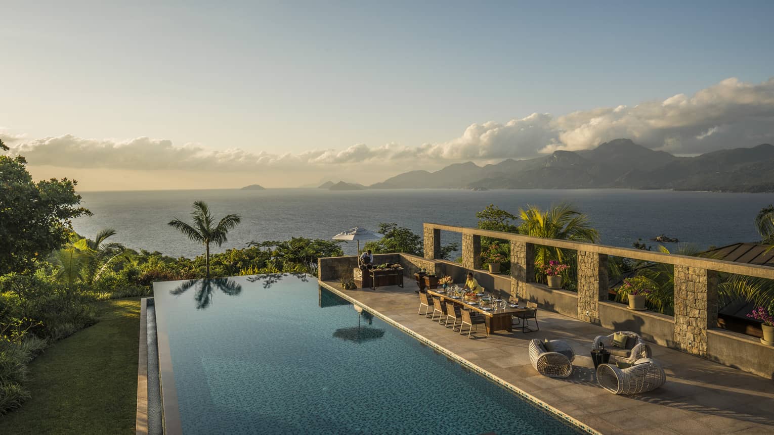 Six-Bedroom Residence Villa long dining table beside swimming pool reflecting palm tree, sunset