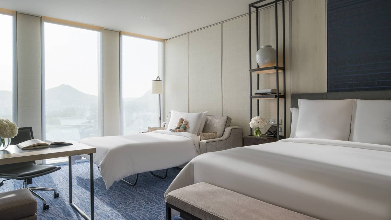 Premier Family Room pull-out sofa with stuffed animals by hotel window between work desk, bed