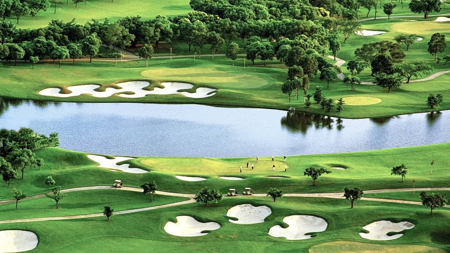 Golf greens with sand traps, large pond, trees