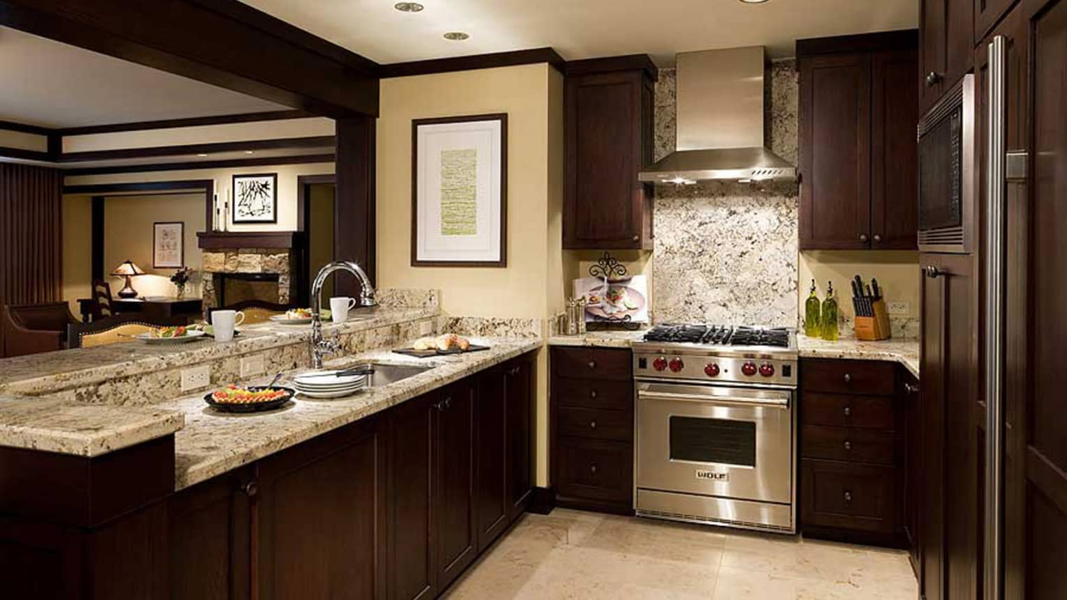 Kitchen with dark wood cupboards, marble counters, stainless steel stove