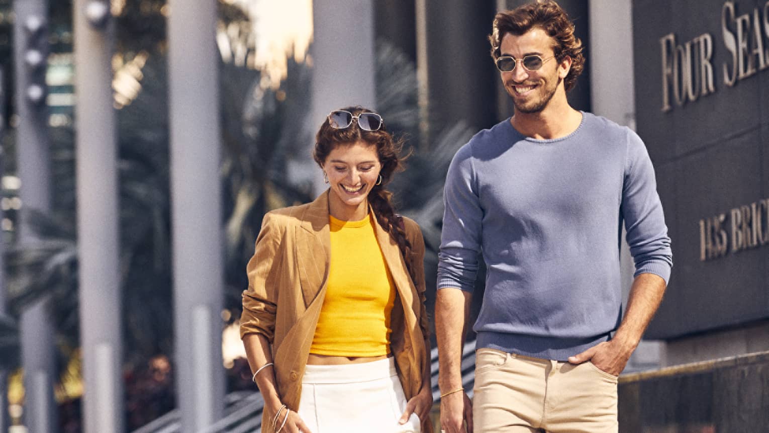 A man and woman walking outside near a hotel.