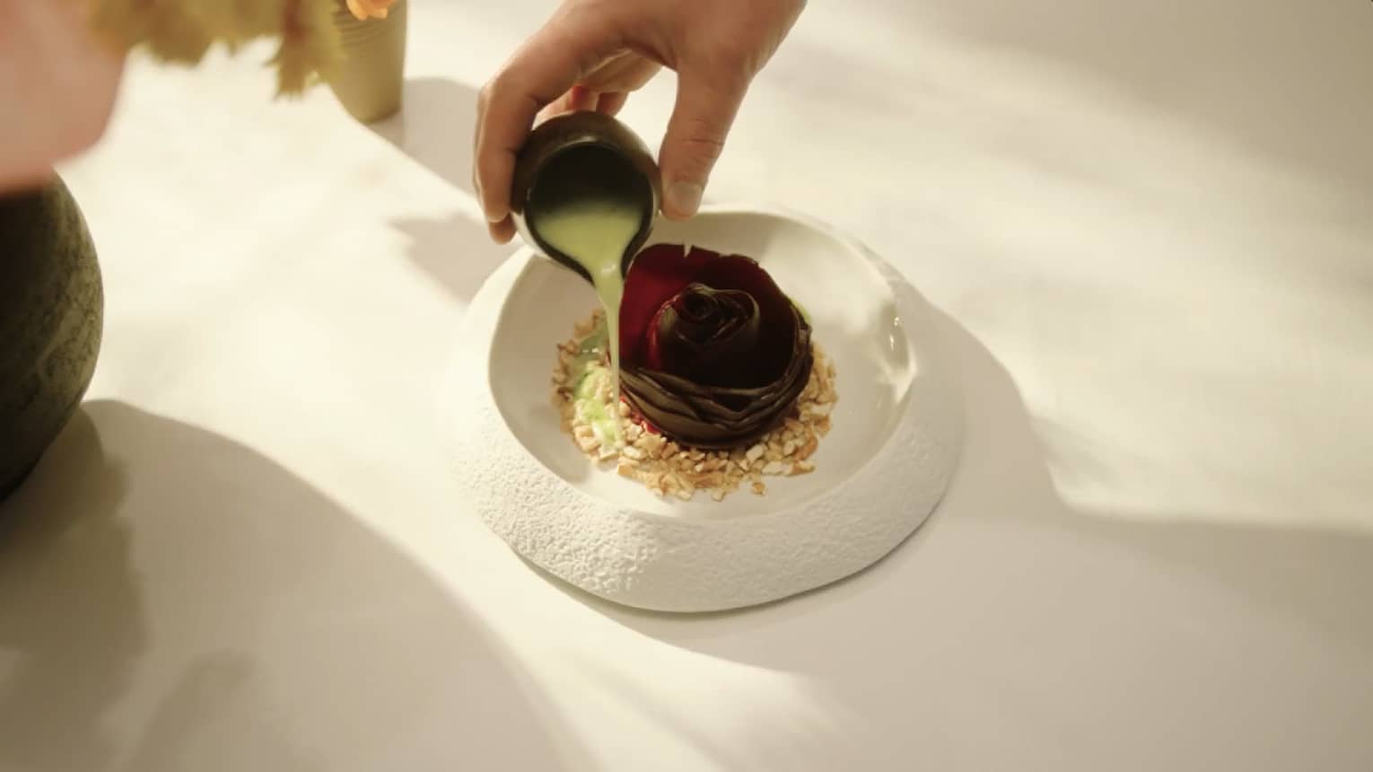 Pouring dressing over food with a flower in the middle.