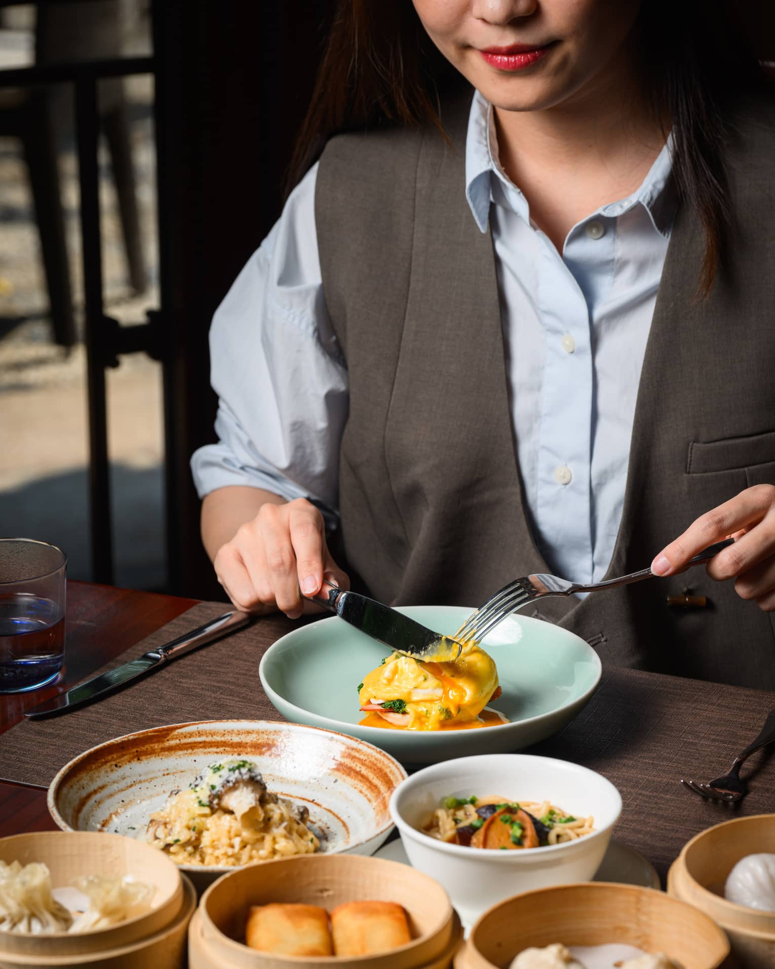 A guest enjoying an egg sandwich, with a mushroom risotto, a noodle dish and a medley of dim sum also laid out on the table.