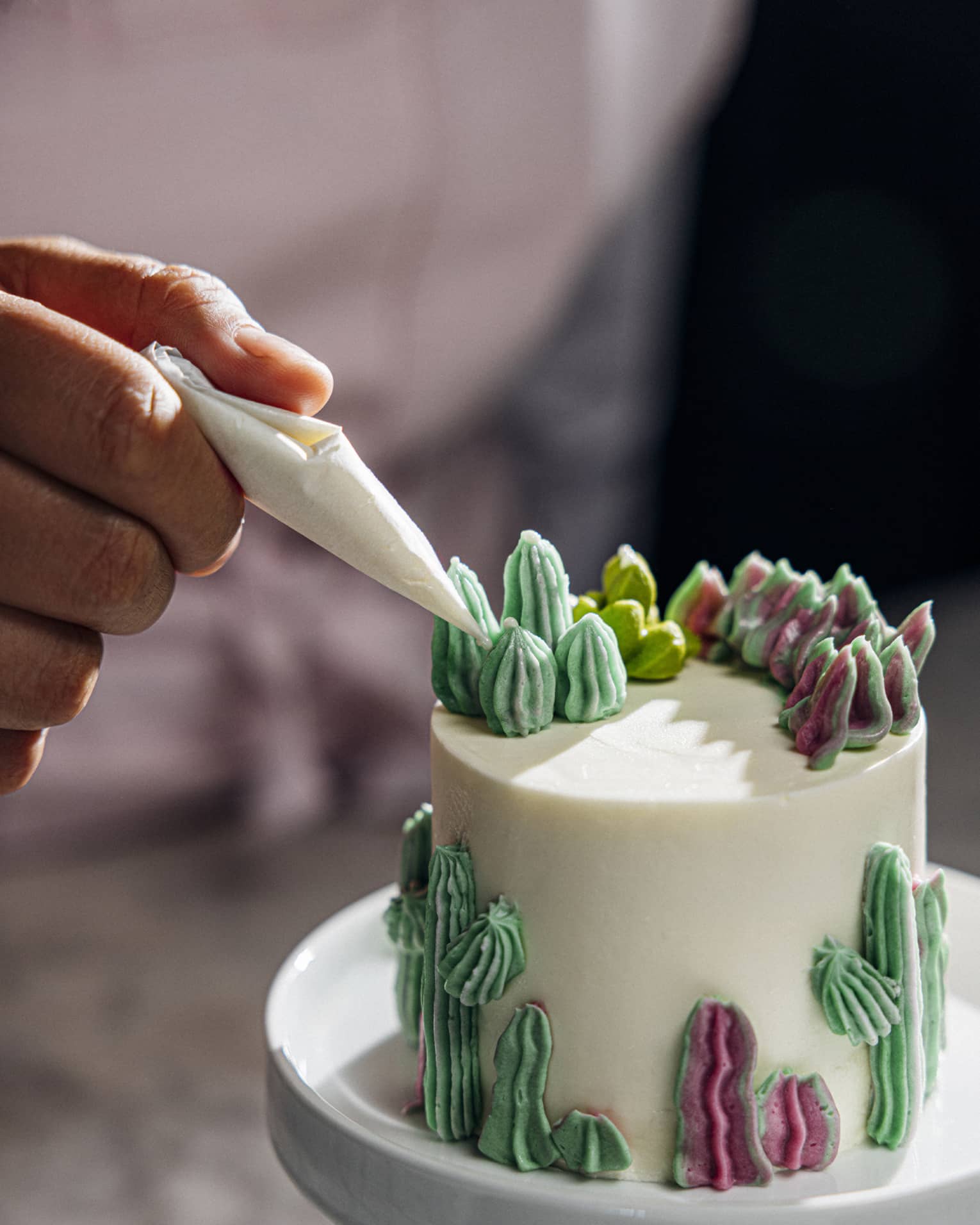 Person decorating a cake with green icing.