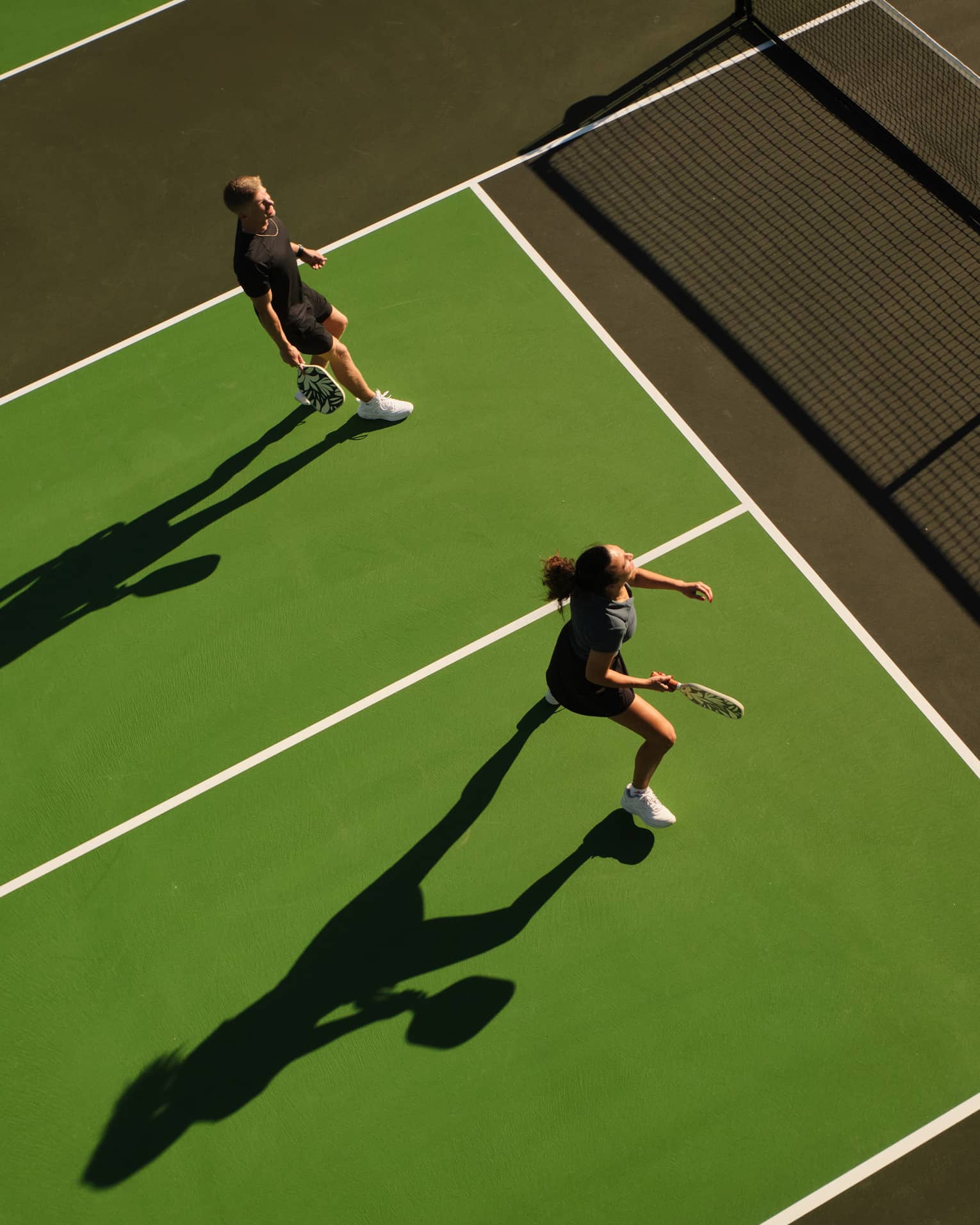 Aerial view of a man and woman playing pickleball on an outdoor court