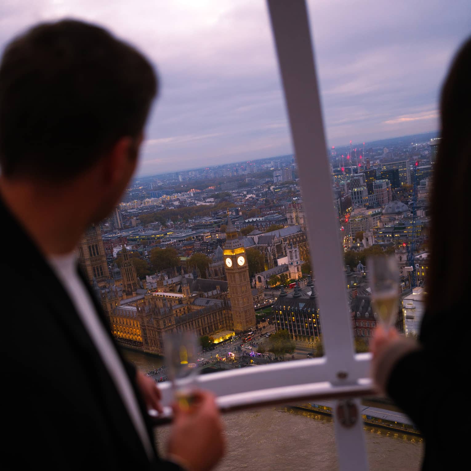People look out over a city from above from a capsule on a large ferris wheel.