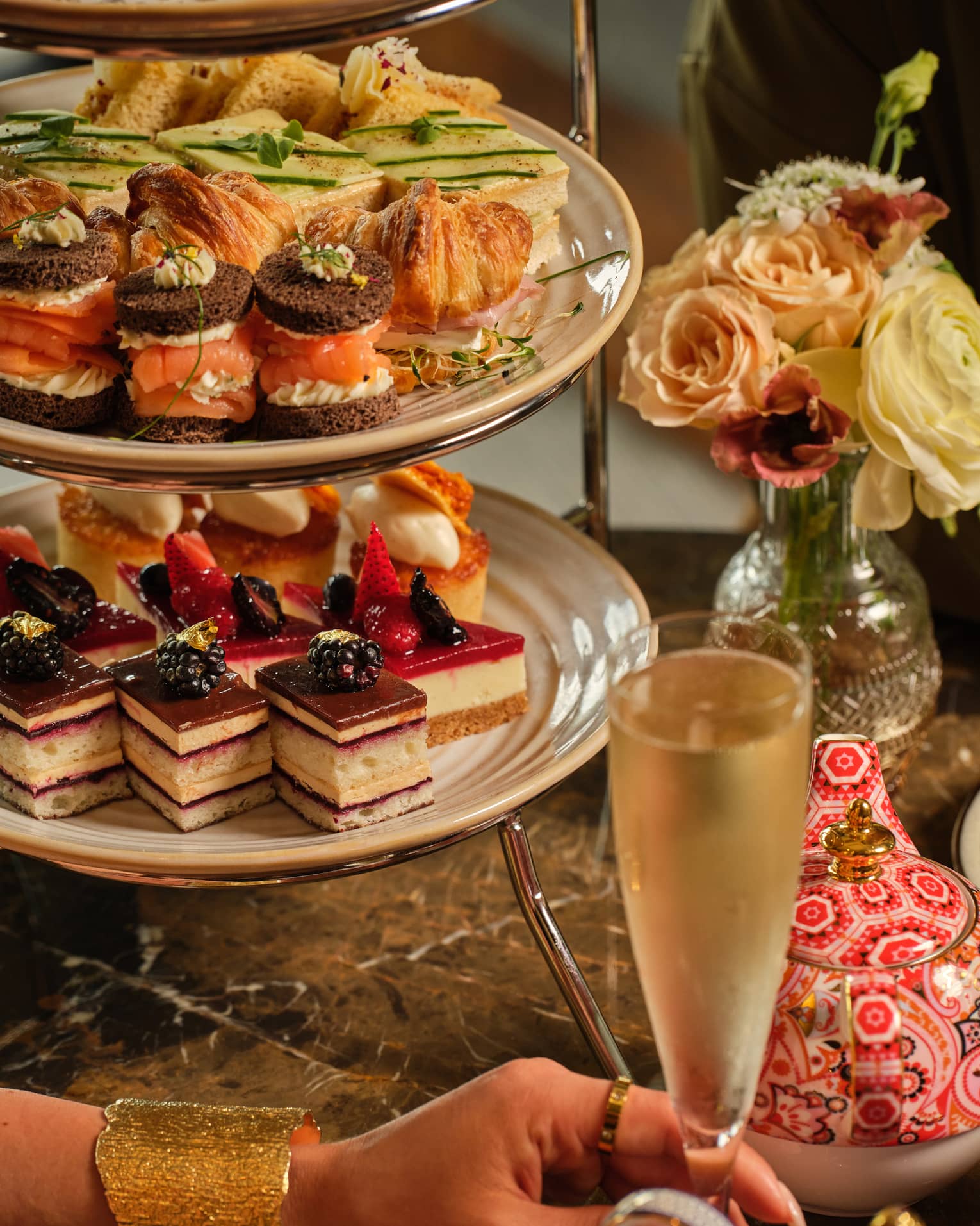 A three-tiered display of sweets beside a vase of flowers