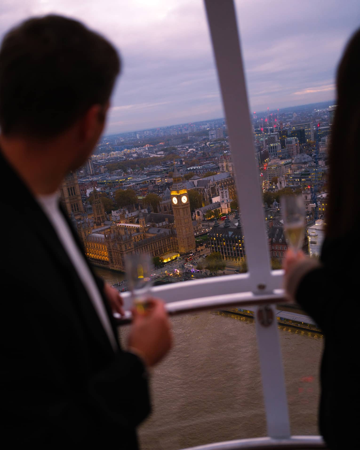 People look out over a city from above from a capsule on a large ferris wheel.