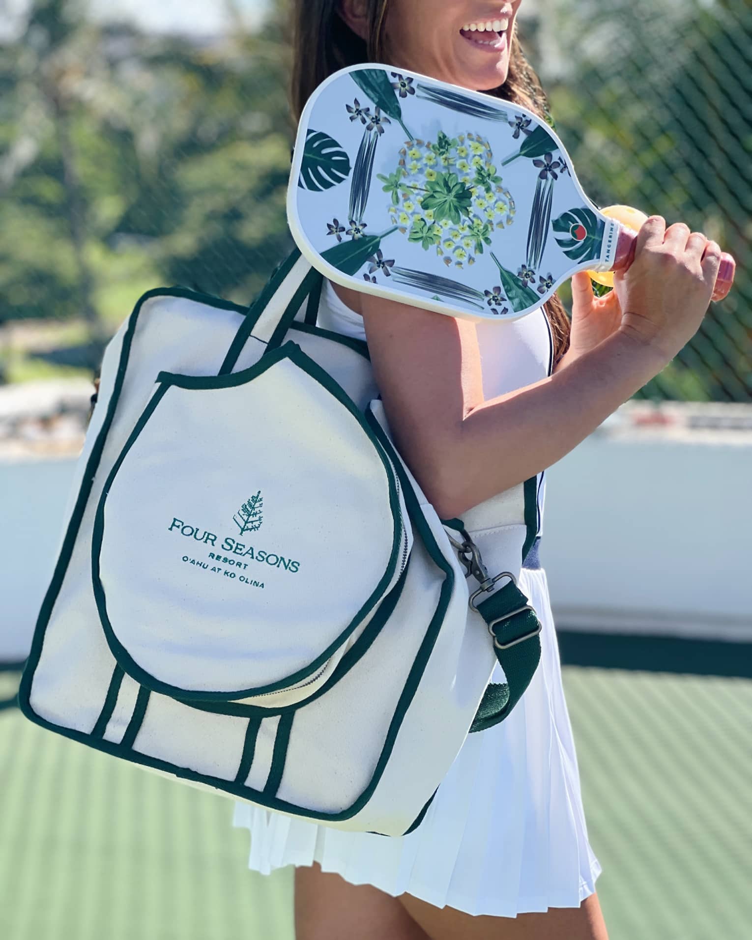 Woman holding pickleball paddle and Four Seasons bag