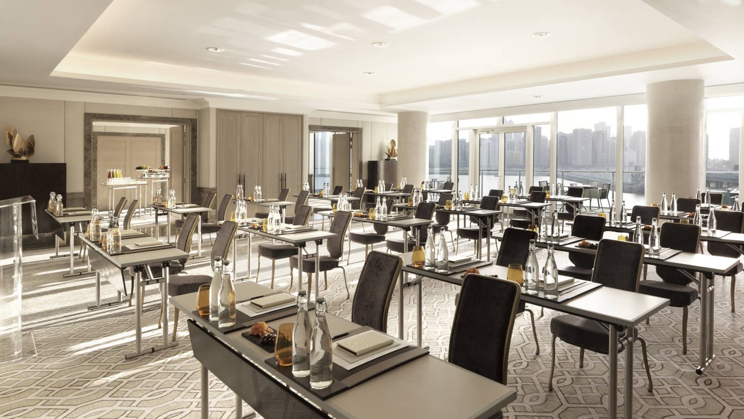 Rows of modern meeting tables with amber glasses, velvet chairs in sunny Al Hosni Meeting Room