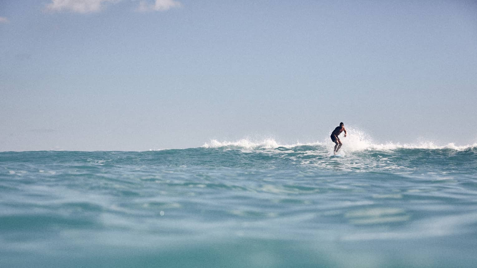 From the water's surface level, view of a man surfing
