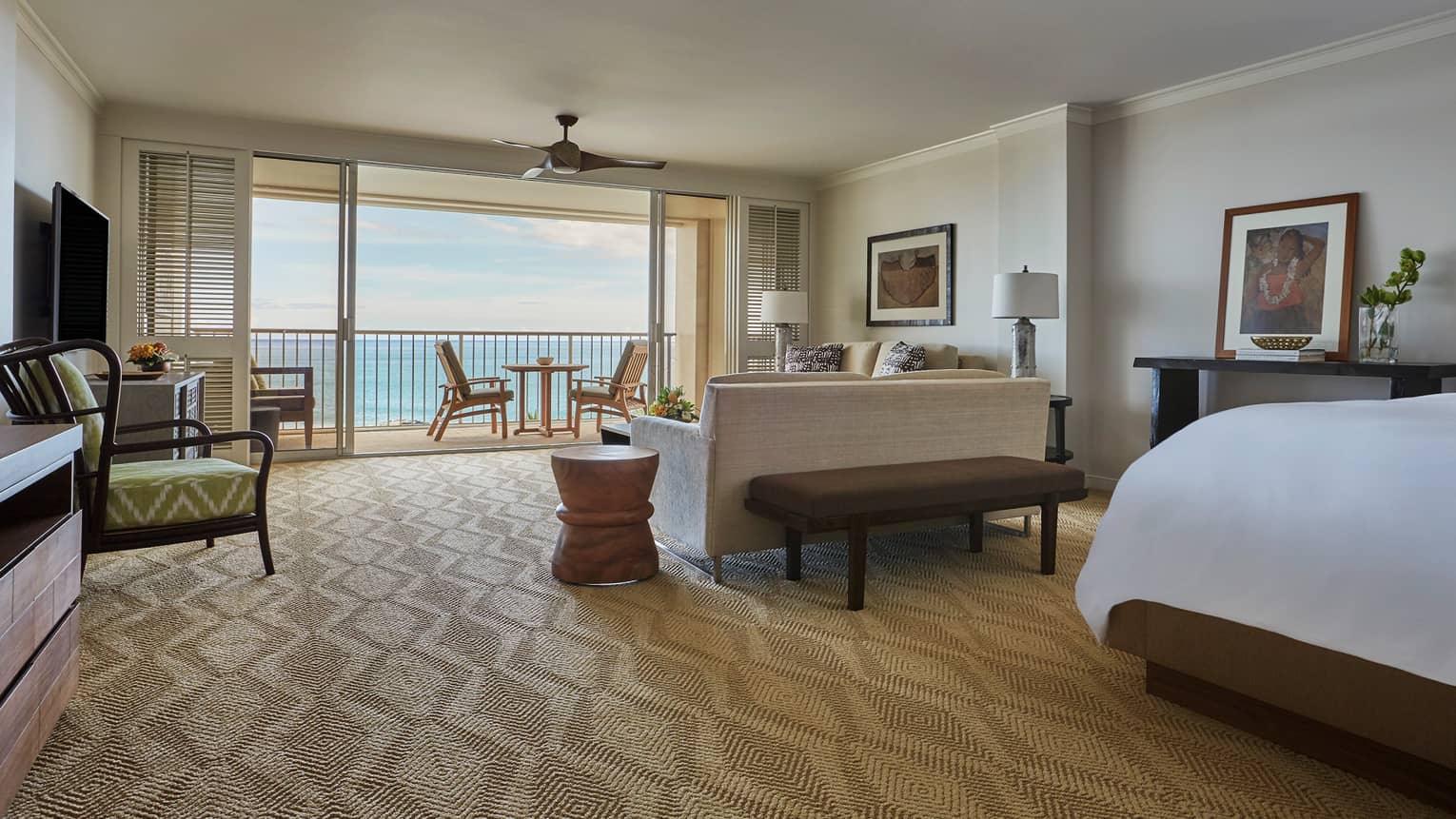 Oceanfront Junior Suite corner of bed behind living room, sofa facing open sliding patio doors