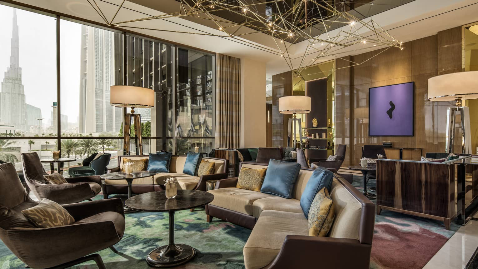 Bright Penrose Lounge with sofas, armchairs, tall lamps, gold geometric sculpture hanging from ceiling