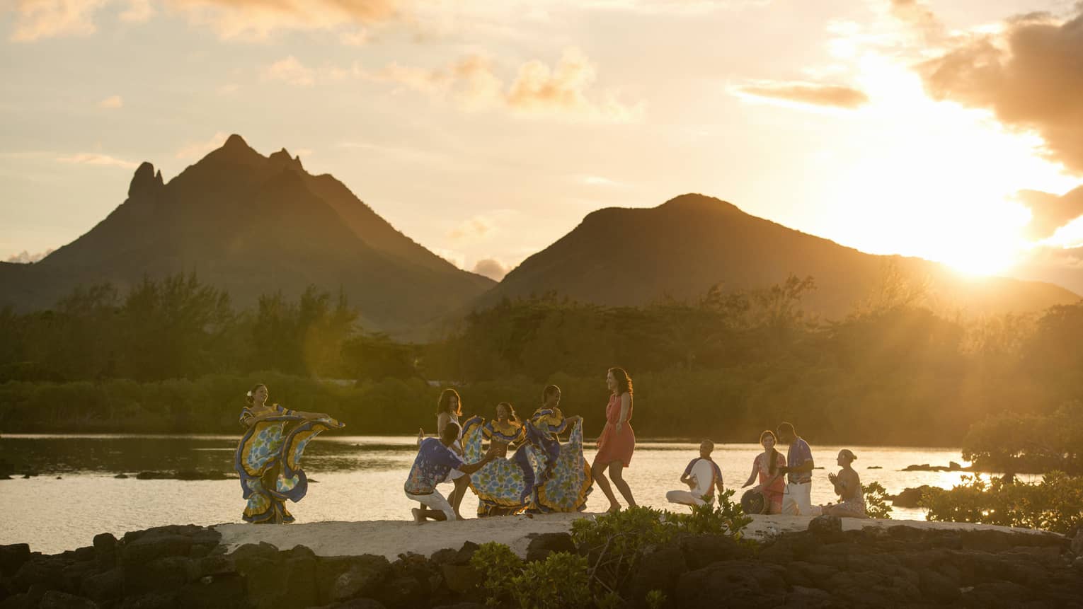 A group of people dancing near water.