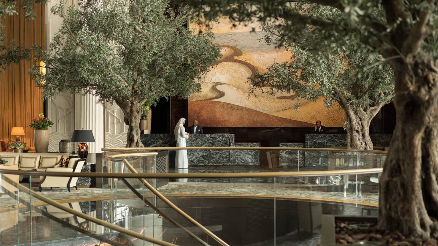 The lobby area featuring several live trees, and a golden staircase. 