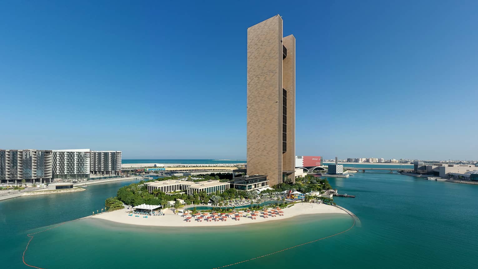A drone shot of the outer facade of the resort, situated on an island with dark blue water surrounding.
