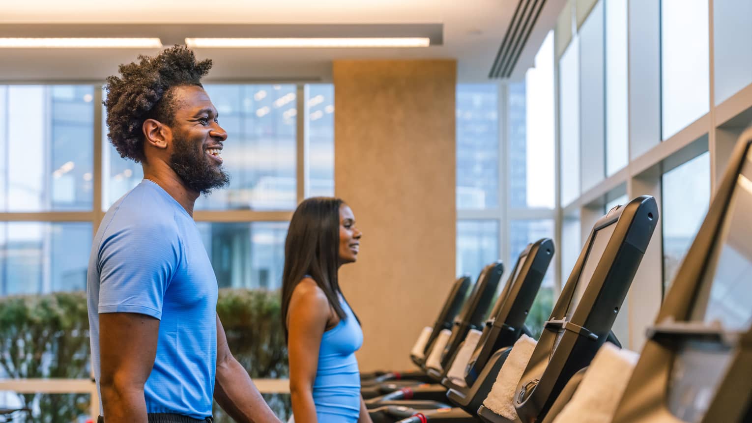 Two guests walking on treadmills in a gym.