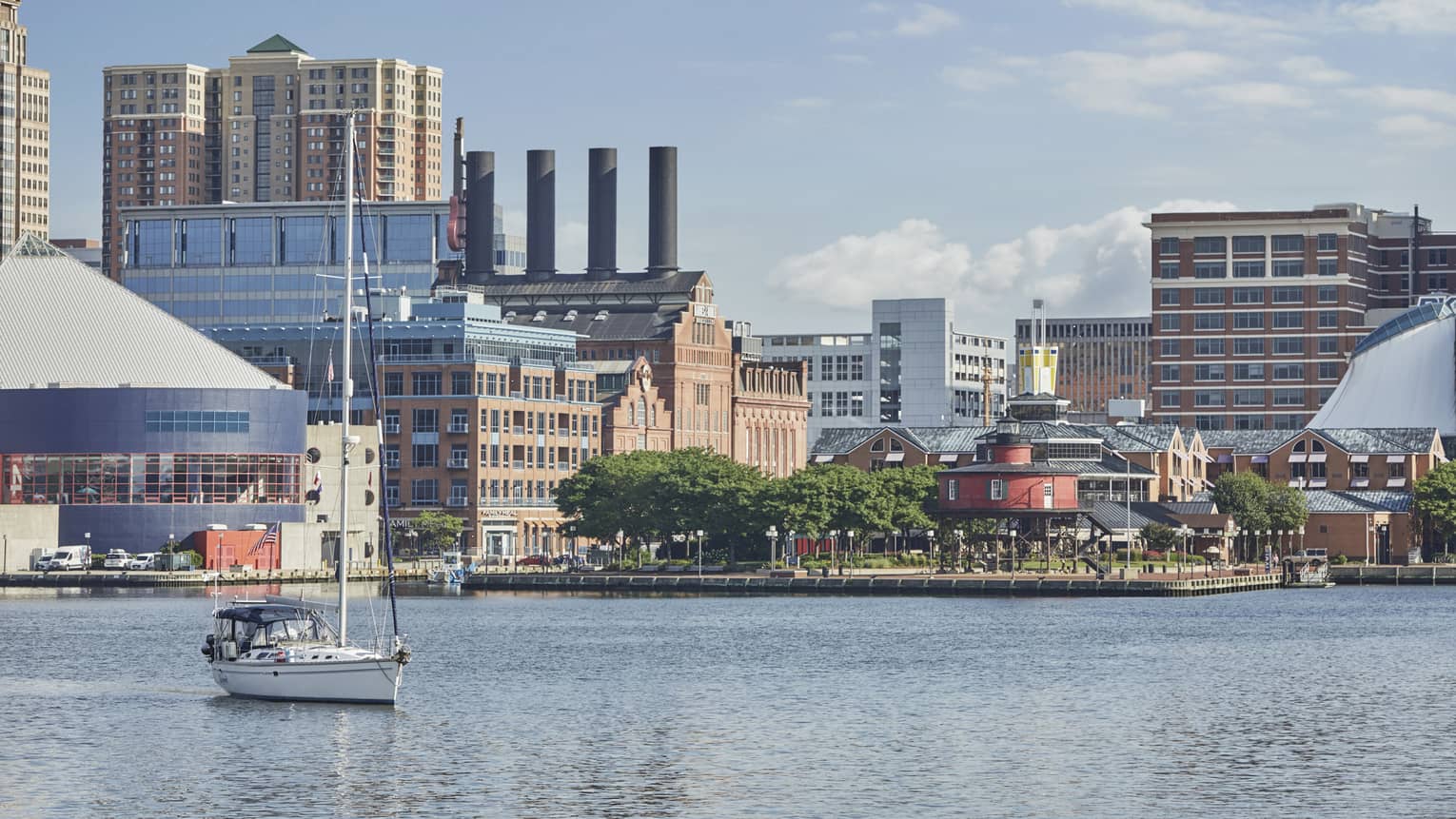 A boat on a river near a city during the day.