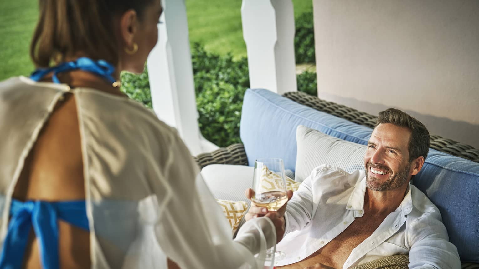 Woman handing man a wine glass on an outdoor patio.