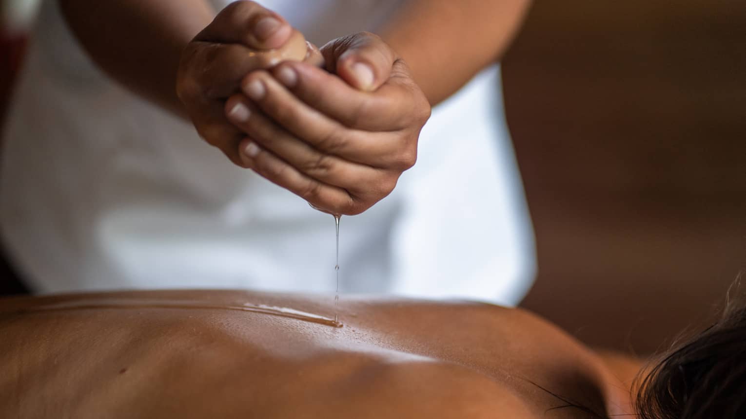 Delicate hands apply oil to a guest's back during a spa treatment