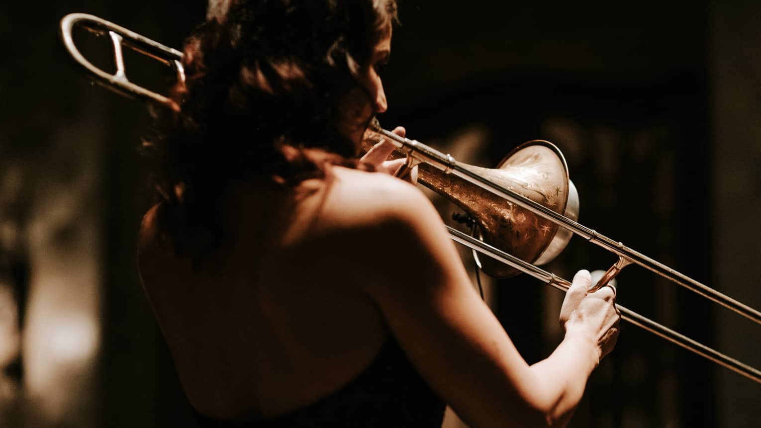 Person playing a trombone in dimly lit space