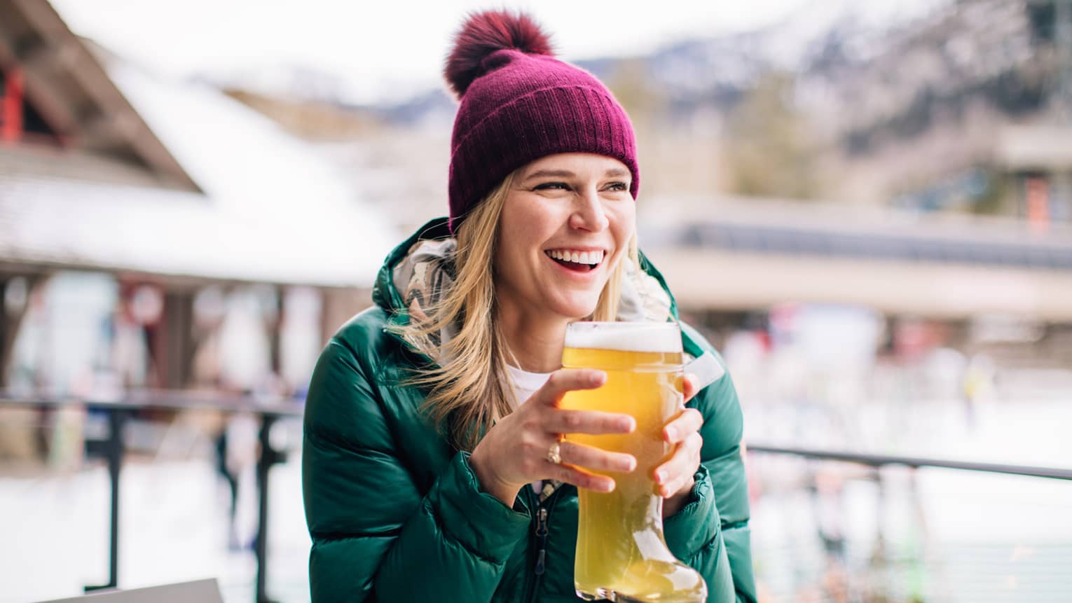 A guest wearing a hat and coat, holding a glass shaped like a boot