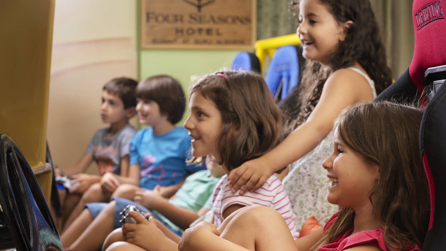 A group of young kids sit around and watch a movie at the Kids Club