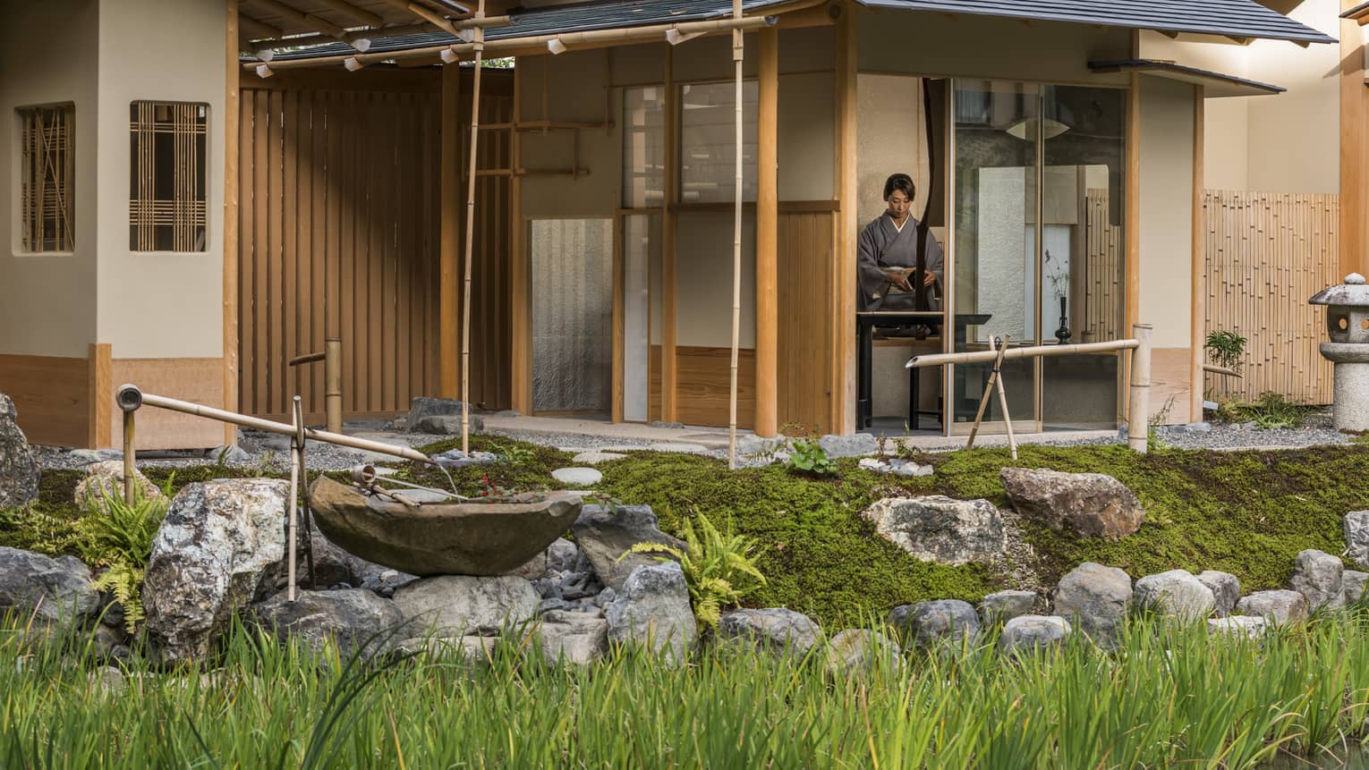 Rock garden, fountain in front of Shakusui tei building, woman in robe behind window