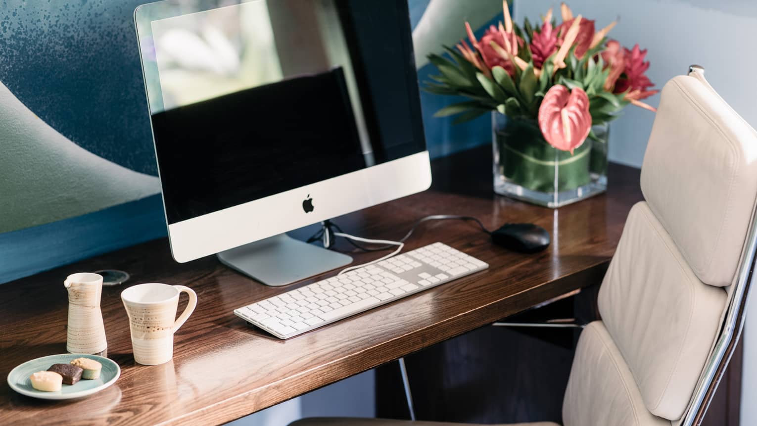 Computer and keyboard on wooden desk with white leather desk chair
