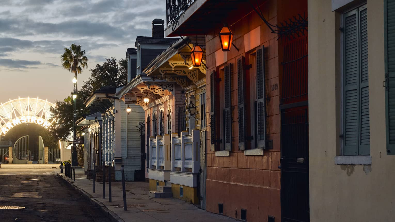 A row of old building on a street with a glowing archway at the end.