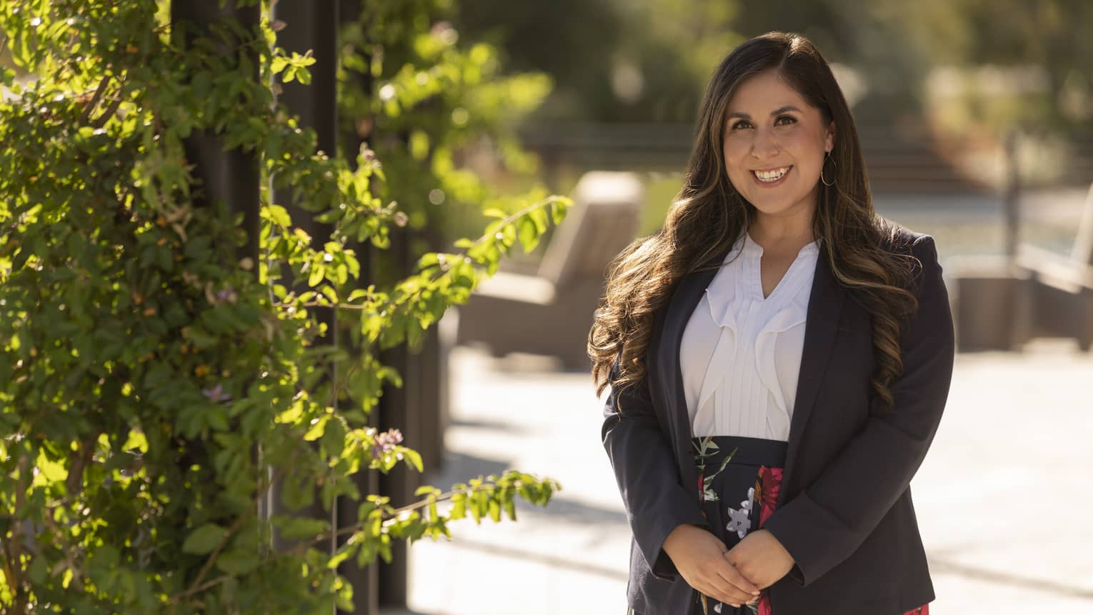 Maritza Koponen in a white blouse and floral skirt standing outside.