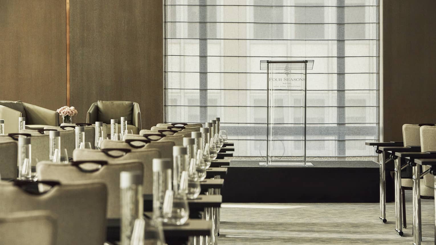 Glass podium beyond rows of meeting tables and chairs in Greenwich Ballroom