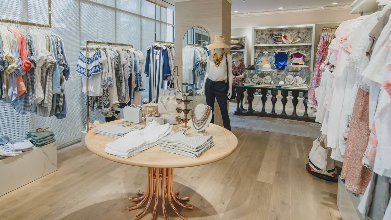 Caprice retail store with clothing racks, display table, mannequin with sun hat