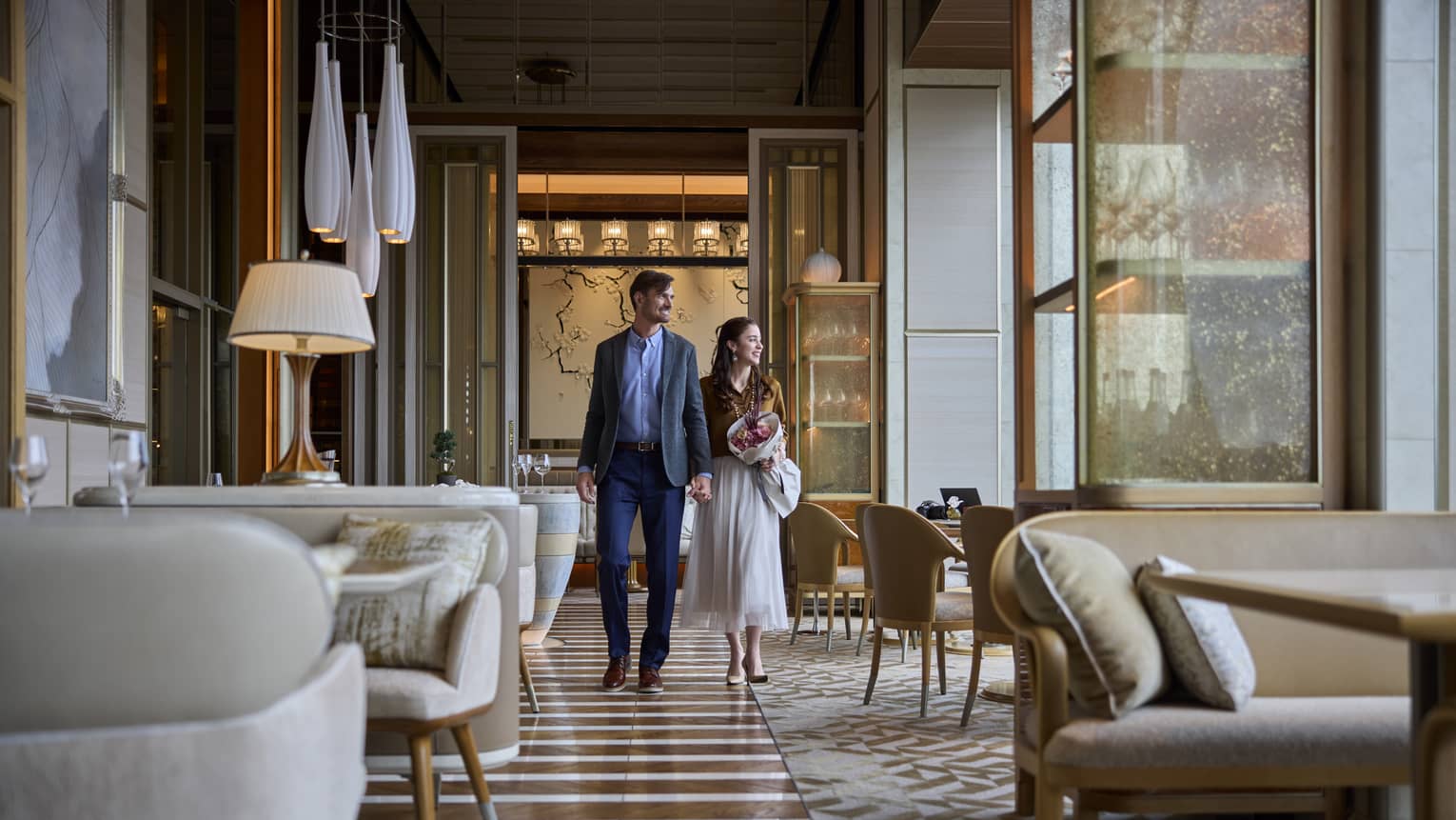 A couple walks hand in hand inside est, a French restaurant in Tokyo, enjoying its elegant and refined ambiance.