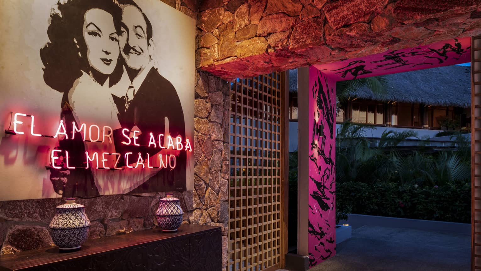 The interior entrance of a bar with a photo of a man and woman hugging and pink lighting.