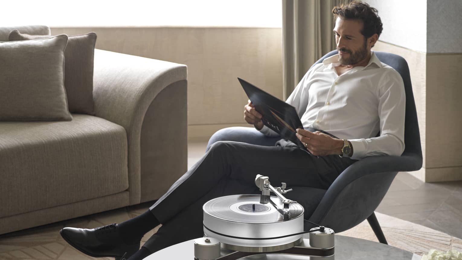 Man lounges in armchair with folder in guest room