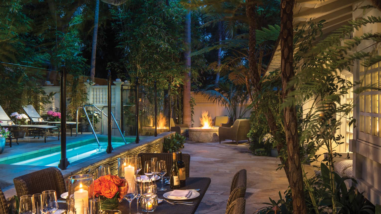 Ty Warner bungalow backyard candle-lit patio dining table by plunge pool, fire pit at night