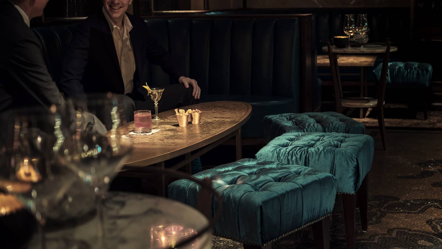 Close-up of men drinking cocktails on lounge table in dimly-lit Charles H dining room