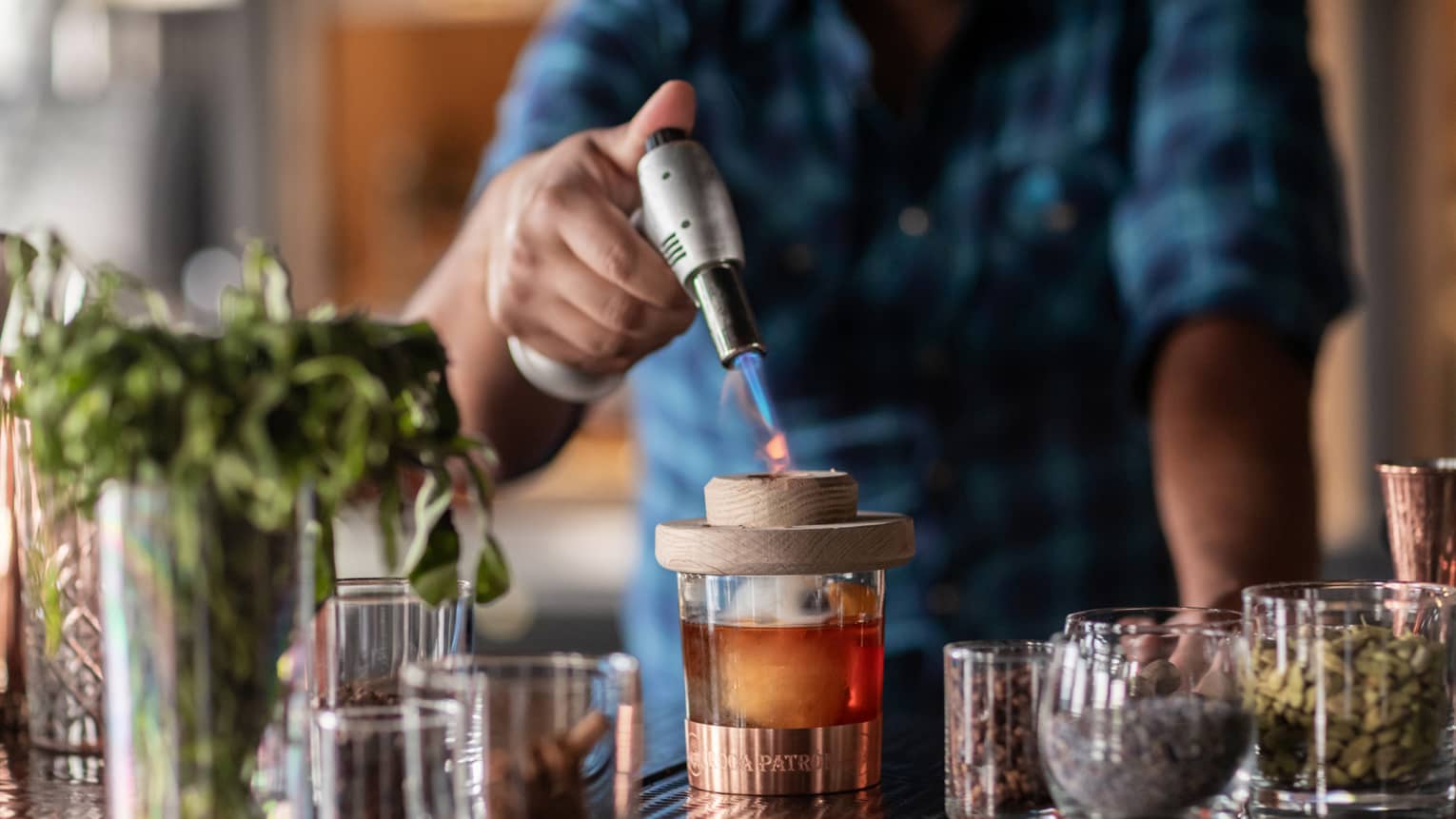 Bartender standing at the bar and using a whiskey torch to make a drink