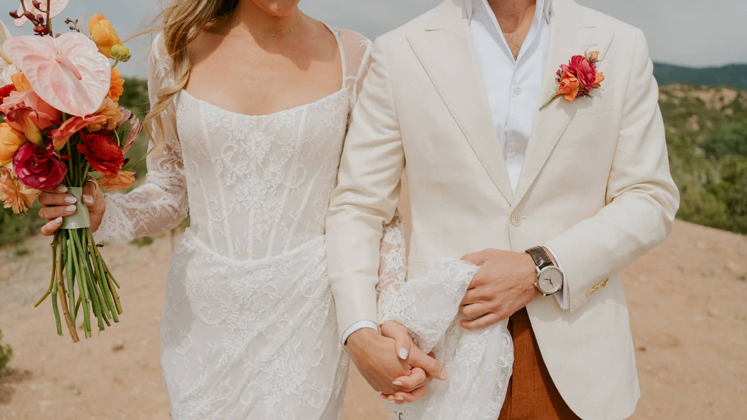 Two guests holding hands, one wearing a wedding dress and the other wearing a suit