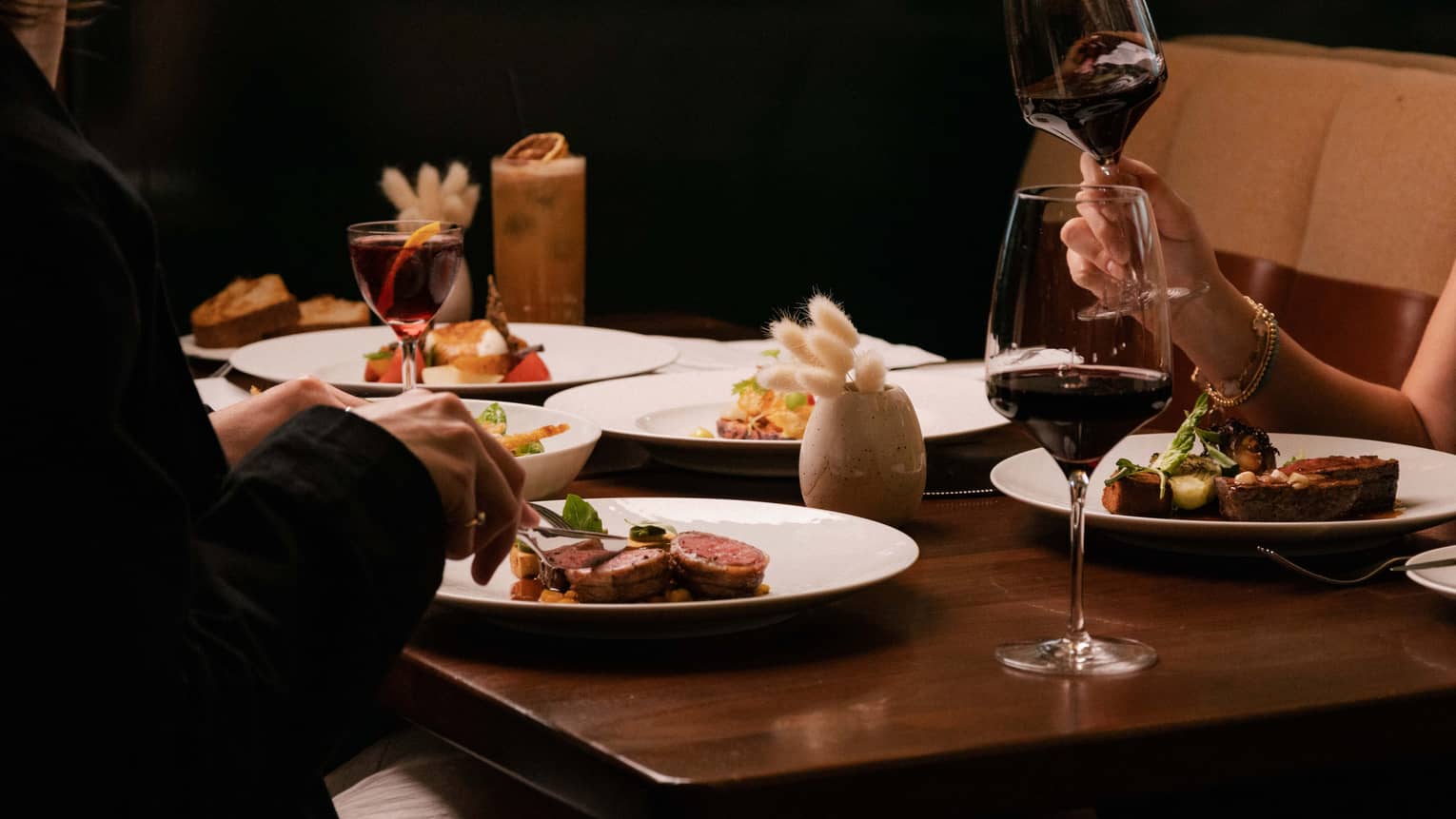 People dine at restaurant table over steak and red wine